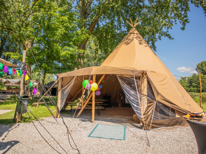 Een grote tipi versierd met vrolijk gekleurde lampionnen en vlaggen