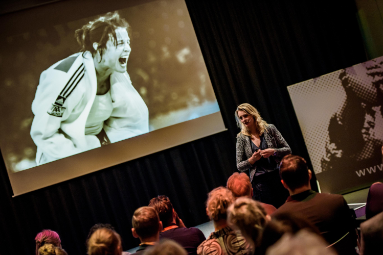 Sportspreker Edith Bos op het podium op Papendal