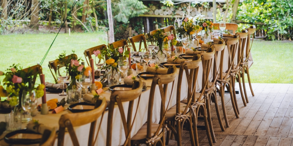 Sfeervolle buiten setting met houten stoelen en gedekte tafel, perfect voor een bruiloft, tuinfeest of diner in de open lucht.
