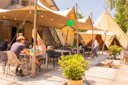 Een gezellig, zonnig terras met tipi en lampjes