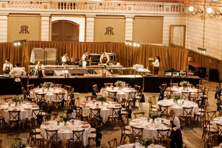 Sfeervol ingerichte evenementenhal met ronde gedekte tafels, witte tafellakens en stoelen, geschikt voor een groot diner, bruiloft of zakelijk event, inclusief professionele tafelaankleding en meubilair van Accuraat Verhuur.