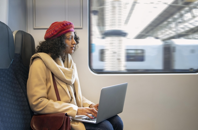 Vrouw met laptop op schoot in de trein