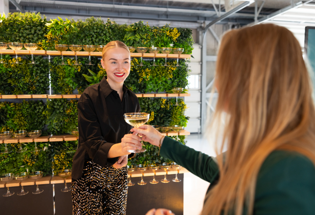 Cateringmedewerker serveert champagne voor groene wand