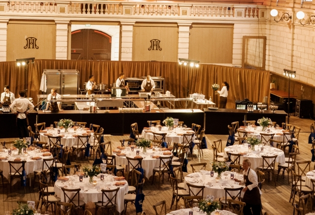 Sfeervol ingerichte evenementenhal met ronde gedekte tafels, witte tafellakens en stoelen, geschikt voor een groot diner, bruiloft of zakelijk event, inclusief professionele tafelaankleding en meubilair van Accuraat Verhuur.