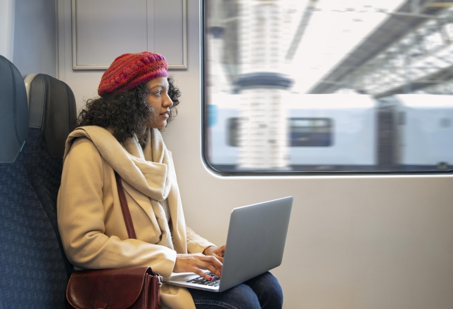 Vrouw met laptop op schoot in de trein